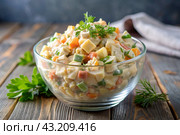 Traditional Russian Olivier salad for a feast on a plate on a wooden countertop. generative AI. Стоковое AI-изображение, AI-художник Photojuli / Фотобанк Лори