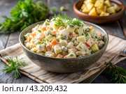 Traditional Russian Olivier salad for a feast on a plate on a wooden countertop. generative AI. Стоковое AI-изображение, AI-художник Photojuli / Фотобанк Лори