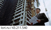 The architect inspects the construction site and the drawings to make sure that the construction process conforms to the architectural plans. Стоковое AI-изображение, AI-художник Ярославский Максим / Фотобанк Лори