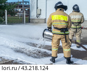 Пожарные в защитной одежде используют пеногенератор для подачи пены для тушения пожара. Пена для тушения пожара. Служба спасения. Пожарные тушат пожар. Стоковое фото, фотограф Эдуард Белкин / Фотобанк Лори