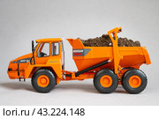 Грузовой самосвал Doosan южнокорейского производства — игрушечная миниатюрная модель с землей в кузове на сером фоне (2023 год). Редакционное фото, фотограф Дорощенко Элла / Фотобанк Лори