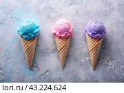 Sweet dessert. Ice cream cones with different flavors. Blue, pink, purple ice cream on a background of three pastel colors: blue, pink and purple. Стоковое AI-изображение, AI-художник Photojuli / Фотобанк Лори