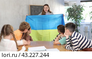 Group of interested preteen learners and young female teacher with flag of Ukraine in classroom of academy. Стоковое видео, видеограф Яков Филимонов / Фотобанк Лори