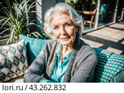Minimalism. A studio portrait of a stylish, elegant elderly woman, a pensioner of 70 years old, in an interior and clothes of calm tones. The concept of the elderly. Стоковое AI-изображение, AI-художник Photojuli / Фотобанк Лори