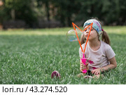 Cute happy girl playing with soap bubbles on a summer day. A child in the fresh air, in nature. The concept of a happy childhood and a holiday. Стоковое фото, фотограф Photojuli / Фотобанк Лори