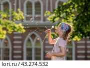A happy beautiful 5-year-old girl blowing on a dandelion on a sunny summer evening. The child is outdoors, in nature. The setting sun. Стоковое фото, фотограф Photojuli / Фотобанк Лори