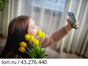 happy stylish fat plumb brunette girl making selfie with yellow tulips in room. happy young lady on International women's day. young hipster woman. Стоковое фото, фотограф Кривошеина Елена Леонидовна / Фотобанк Лори