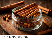 Ceylon cinnamon sticks in glass plate on wooden board, rustic style. Still life natural food of sri lankan cinnamon sticks on table at grey wall. Delicious tasty healthy concept. Copy ad text space. Стоковое AI-изображение, AI-художник Aleksandr Golubev / Фотобанк Лори