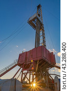 Drilling rig for deep drilling for oil and gas with a sunbeam at the base. The image of bursting energy of the subsoil. Many drill pipes installed vertically. Стоковое фото, фотограф Владимир Ендовицкий / Фотобанк Лори