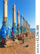 Baikal Lake. Olkhon Island. 13 Serge ritual pillars with blue and colored ribbons of Buddhists and tourists in Khuzhir village. Tourist attraction of Cape Burkhan. Pigeons are waiting for treats from tourists (2023 год). Стоковое фото, фотограф Виктория Катьянова / Фотобанк Лори