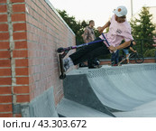 Moscow, Russia - September 29, 2021: Teenager performs trick in the city skate park. Push scooter. Vertical wall riding. Extreme sports is popular among youth. Редакционное фото, фотограф YuryKara / Фотобанк Лори