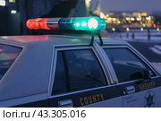Police patrol at night. City street in winter. Harassment of the offender. To protect and serve. American car, 80s. Offense against the law. Police forces. Defocused cityscape as background. (2020) Редакционное фото, фотограф YuryKara / Фотобанк Лори