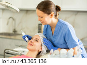 Adult woman cosmetologist doing microcurrent procedure to young woman. Стоковое фото, фотограф Яков Филимонов / Фотобанк Лори