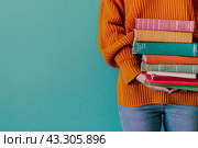 An unidentified girl in a red sweater holds a stack of books on a green background. Copy space. Стоковое AI-изображение, AI-художник Ярославский Максим / Фотобанк Лори