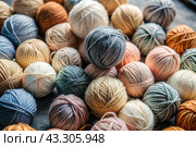 The background is made of balls of wool yarn . Needlework, textiles, knitting. Winter season, small business, handmade clothes. Стоковое AI-изображение, AI-художник Photojuli / Фотобанк Лори