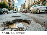 The terrible condition of the roads. A hole in the asphalt on a city street. Road repairs. A city street of poor quality. Стоковое AI-изображение, AI-художник Photojuli / Фотобанк Лори