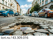 The terrible condition of the roads. A hole in the asphalt on a city street. Road repairs. A city street of poor quality. Стоковое AI-изображение, AI-художник Photojuli / Фотобанк Лори