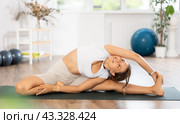 Young woman yoga trainer performing side bend pose on black rug. Стоковое фото, фотограф Яков Филимонов / Фотобанк Лори