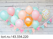 A collection of colorful balloons dangle from a thread against a wooden backdrop. Стоковое AI-изображение, AI-художник Юрий Поздников / Фотобанк Лори