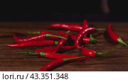 Fresh Red Chili Peppers on Wooden Surface, a vibrant and fiery addition to any culinary dish. Стоковое видео, видеограф Victor Kaprov / Фотобанк Лори