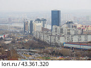 Город Красноярск, Красноярский край, Сибирь, Россия. Вид сверху на большой сибирский город. Среди домов возвышается современное высотное здание. Вдали за пеленой дождя видны городские кварталы. (2023 год). Стоковое фото, фотограф Андрей Степанов / Фотобанк Лори