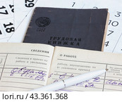 Подсчет трудового стажа. Раскрытая трудовая книжка на фоне листков календаря. Выход на пенсию. Стоковое фото, фотограф Татьяна Т / Фотобанк Лори