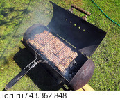 Приготовление мяса-гриль на мангале, изготовленном из старого газового баллона. Стоковое фото, фотограф Александр Замараев / Фотобанк Лори