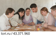 Cheerful adult students playing board game excitedly sitting around the table. Стоковое видео, видеограф Яков Филимонов / Фотобанк Лори