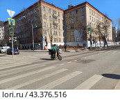 Курьер на электровелосипеде. Пятиэтажный жилой дом (1951 г.). 5-я Парковая улица, 38. Пятиэтажное кирпичное административное здание (1951 г.). Измайловский бульвар, 13. Москва (2024 год). Редакционное фото, фотограф lana1501 / Фотобанк Лори