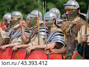 Soldiers of the first Roman Legion stand in a row in ammunition and with shields, historical reconstruction . The Times and Epochs Festival 2024 - Moscow, Russia, June 16, 2024. Редакционное фото, фотограф Андрей Журавлев / Фотобанк Лори