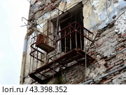 Old rusty metal balcony on a deteriorating brick building. Стоковое AI-изображение, AI-художник Антон Гвоздиков / Фотобанк Лори