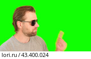 Surprised wow man over green background. Adult bearded guy in sunglasses gesturing on green screen chromakey. Handsome male looking pointed side to product placement isolated greenscreen. For Keying. Стоковое видео, видеограф Марина Демидюк / Фотобанк Лори