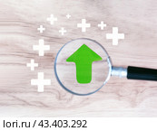 Концепция роста и приумножения. Увеличенная лупой зеленая стрелка направлена вверх. Стоковое фото, фотограф Татьяна Т / Фотобанк Лори
