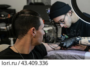 Professional tattoo artist stuffs a tattoo on the man's hand. Tattoo artist at work. Tattoo creation process. Art and creativity. Стоковое фото, фотограф Елена Никишина / Фотобанк Лори