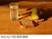 A glass of vodka with pieces of black bread and pickled cucumber. wooden background. drunkenness concept. Стоковое фото, фотограф Дмитрий Львович Алферов / Фотобанк Лори