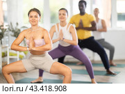 Girl performing Goddess Pose with hands in namaste in yoga class. Стоковое фото, фотограф Яков Филимонов / Фотобанк Лори