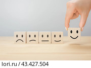 Customer services best excellent business rating experience. Satisfaction survey concept. Hand of businessman chooses a smile wooden cube on gray background. copy space. Стоковое фото, фотограф Павел Муравьев / Фотобанк Лори