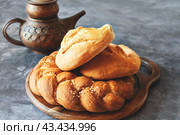 Different types of bread - kalacha, hala - braided loaf with coarse salt. Bread on table with kettle and jug, prepared for consumption. Assortment of handmade bread. Стоковое фото, фотограф Оксана Медведева / Фотобанк Лори