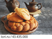 Different types of bread - kalacha, hala - braided loaf with coarse salt. Bread on table with kettle and jug, prepared for consumption. Assortment of handmade bread. Стоковое фото, фотограф Оксана Медведева / Фотобанк Лори
