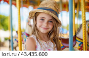 A happy little girl in a sun hat is sitting on a merrygoround, smiling with joy. Стоковое AI-изображение, AI-художник Юрий Поздников / Фотобанк Лори