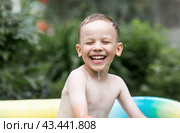 It's a hot day. A cute boy is swimming and splashing in the pool. A happy little boy smiles at the camera. Splashes of water are flying in all directions. The concept of summer holidays with children. Стоковое фото, фотограф Photojuli / Фотобанк Лори