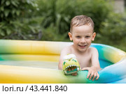 It's a hot day. A cute boy is swimming and splashing in the pool. A happy little boy smiles at the camera. Splashes of water are flying in all directions. The concept of summer holidays with children. Стоковое фото, фотограф Photojuli / Фотобанк Лори