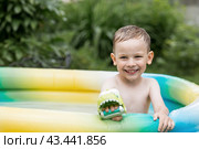 It's a hot day. A cute boy is swimming and splashing in the pool. A happy little boy smiles at the camera. Splashes of water are flying in all directions. The concept of summer holidays with children. Стоковое фото, фотограф Photojuli / Фотобанк Лори