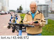 Old man using smartphone to activate e-scooter. Стоковое фото, фотограф Татьяна Яцевич / Фотобанк Лори