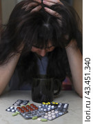 Женщина в тоске над горой таблеток. A middle-aged woman holding her head and staring at the pile of pills in dismay. Стоковое фото, фотограф Ekaterina M / Фотобанк Лори