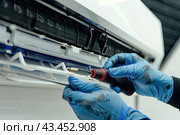 The hands of an unrecognized master repair the air conditioner. Close-up. The concept of repair services. Стоковое AI-изображение, AI-художник Ярославский Максим / Фотобанк Лори