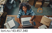 A woman works on her laptop in a cluttered home office. She is focused on her work and surrounded by papers and other work-related items. Стоковое AI-видео, аниматор Данила Большаков / Фотобанк Лори