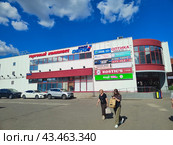 Торговый центр с рекламными вывесками и парковка, Москва, прохожие (2024 год). Редакционное фото, фотограф Ирина Терентьева / Фотобанк Лори