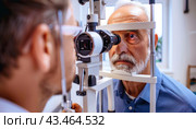 A photograph captures the moment when an elderly man visits an eye doctor for an eye examination. Стоковое AI-изображение, AI-художник Юрий Поздников / Фотобанк Лори
