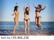 Three beautiful women having fun running and jumping on a beach. Стоковое фото, фотограф Raquel Corcoles Mendez / Фотобанк Лори